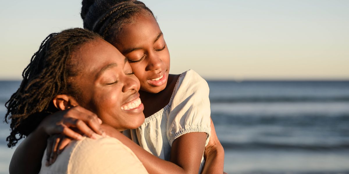 A mother embracing her daughter on a sunny day.