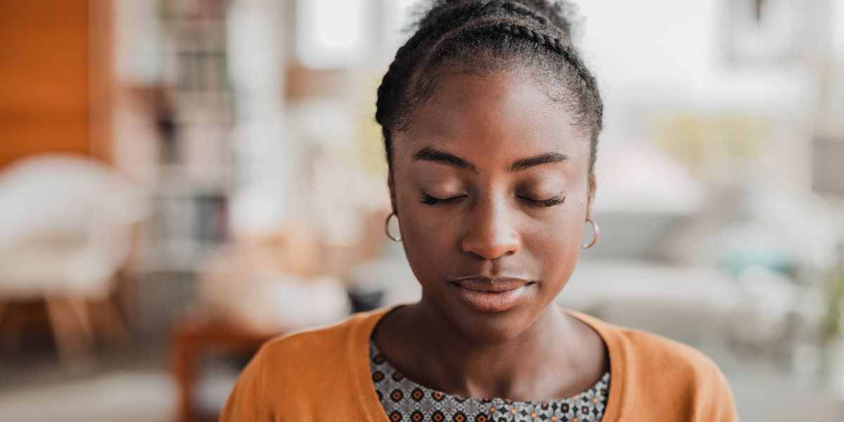 A young woman peacefully praying in her home.