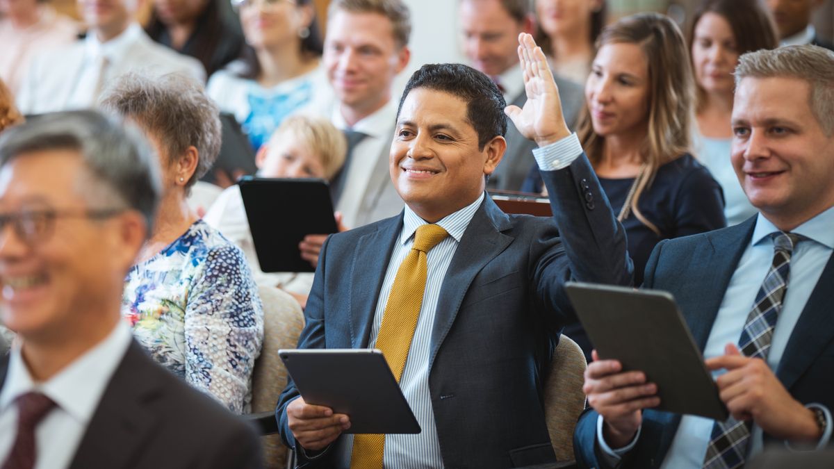 A brother raising his hand to make a comment during a congregation meeting.
