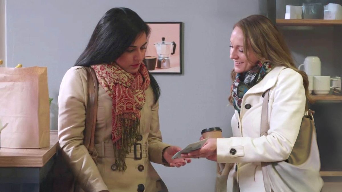 A scene from the video “Jehovah ‘Is Not Far Off.’ ” A sister giving a tract to a woman in a coffee shop.