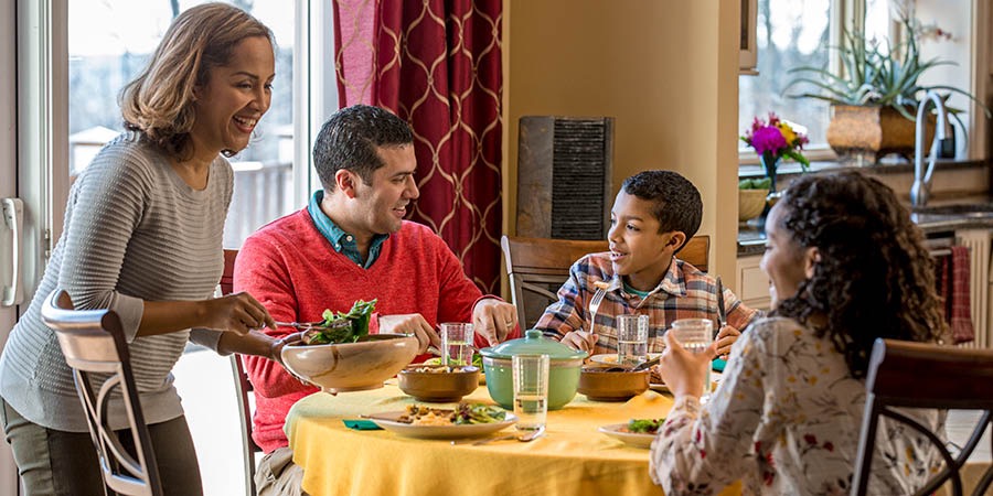 ’n Gesin gesels lekker om die tafel terwyl hulle eet