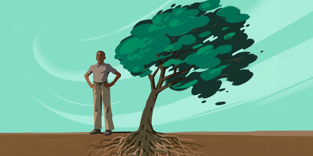 ’n Jong man staan langs ’n boom wat deur die wind gewaai word