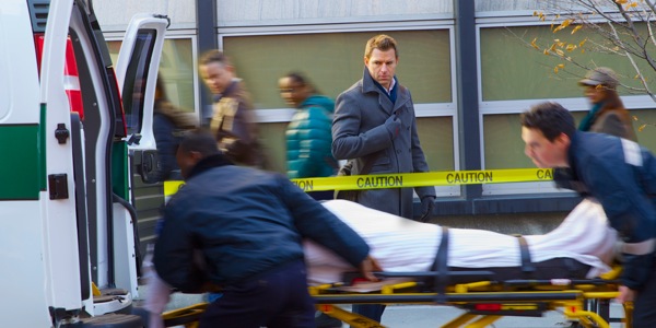 Iemand word in ’n ambulans gelaai terwyl verbygangers toekyk
