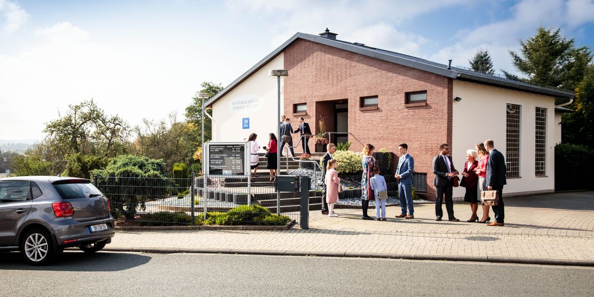 ’n Groep Getuies van Jehovah gesels lekker met mekaar buite ’n Koninkryksaal.