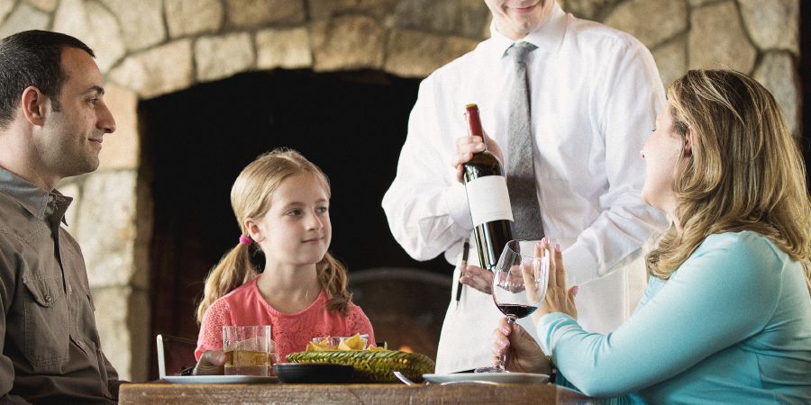 ’n Klein meisie sien hoe haar ma nee sê wanneer ’n kelner vir haar nog wyn aanbied