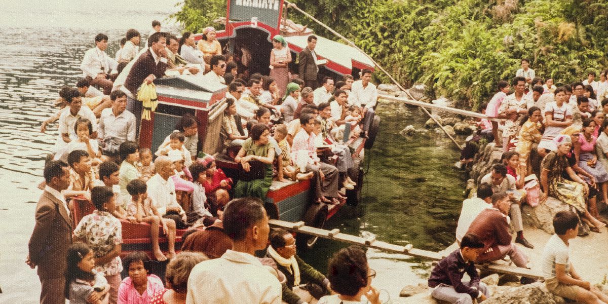 ’n Byeenkoms in Indonesië gedurende die verbod waartydens deel van die gehoor vanaf ’n boot luister 