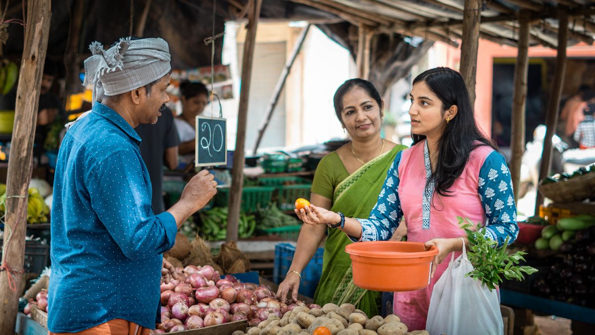 এজনী যুৱতী ভনীয়ে নিজৰ মাৰ লগত শাক-পাচলিৰ দোকানত দৰদাম কৰি আছে।