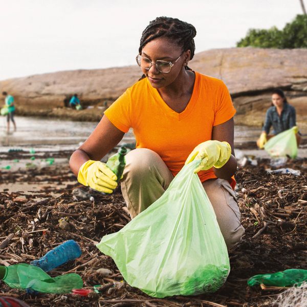 A group of people picking up trash at a beach.