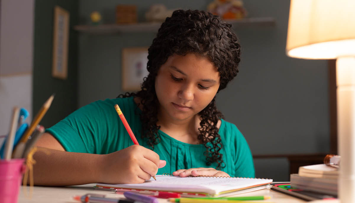 A young girl writing in a notebook.