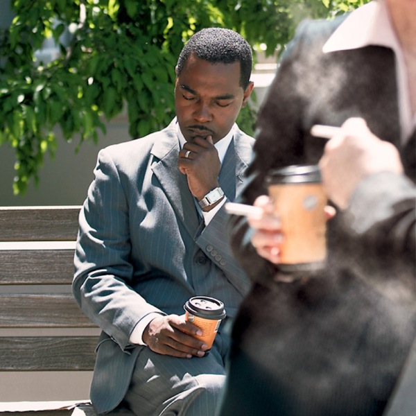 A man praying to resist the urge to smoke while others around him are smoking