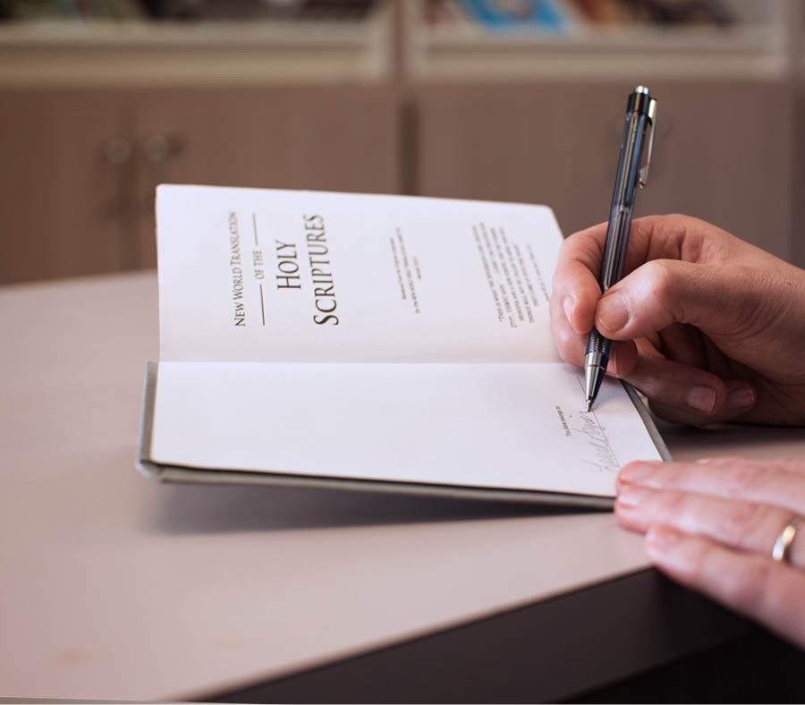 One of Jehovahʼs Witnesses writes his name in his personal copy of the Bible