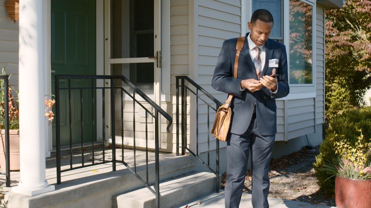 A scene from the video “Imitate the Faithful, Not the Faithless​—Moses, Not Pharaoh.” A brother on his way out to his assigned convention receives an urgent call from work.