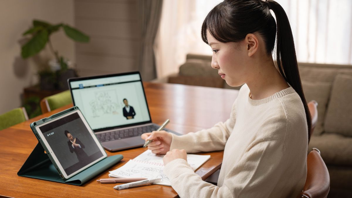 A young sister doing personal study. She has her Bible open and watches a whiteboard animation video on a tablet.
