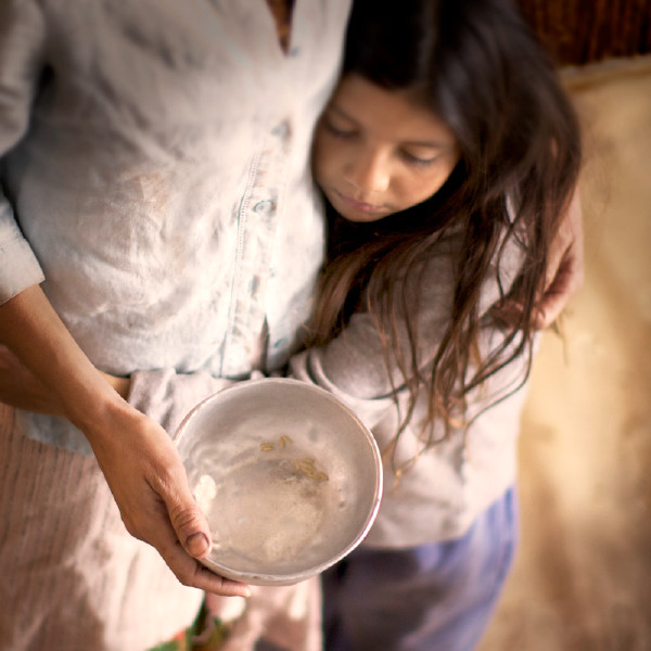 Qadın boş qabı əlində tutur və balaca qızı qucaqlayır