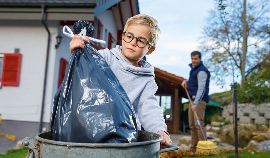 A boy puts trash in a bin