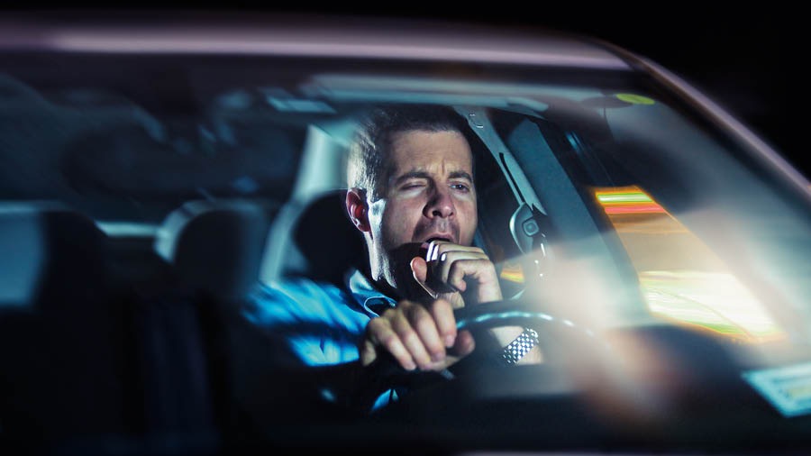A brother yawning while driving late at night.