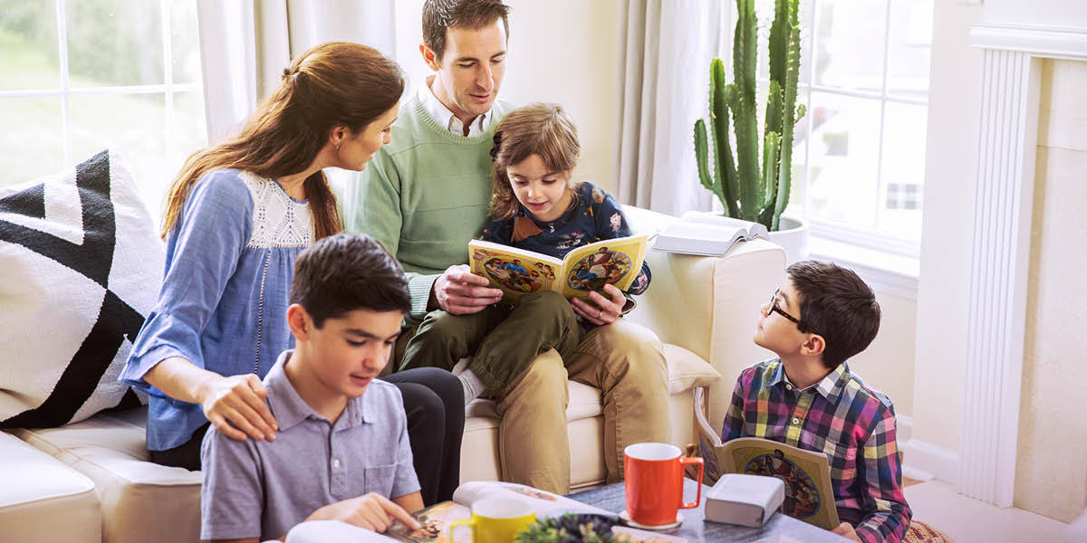 Parents using the book “Learn From the Great Teacher” to study with their children.
