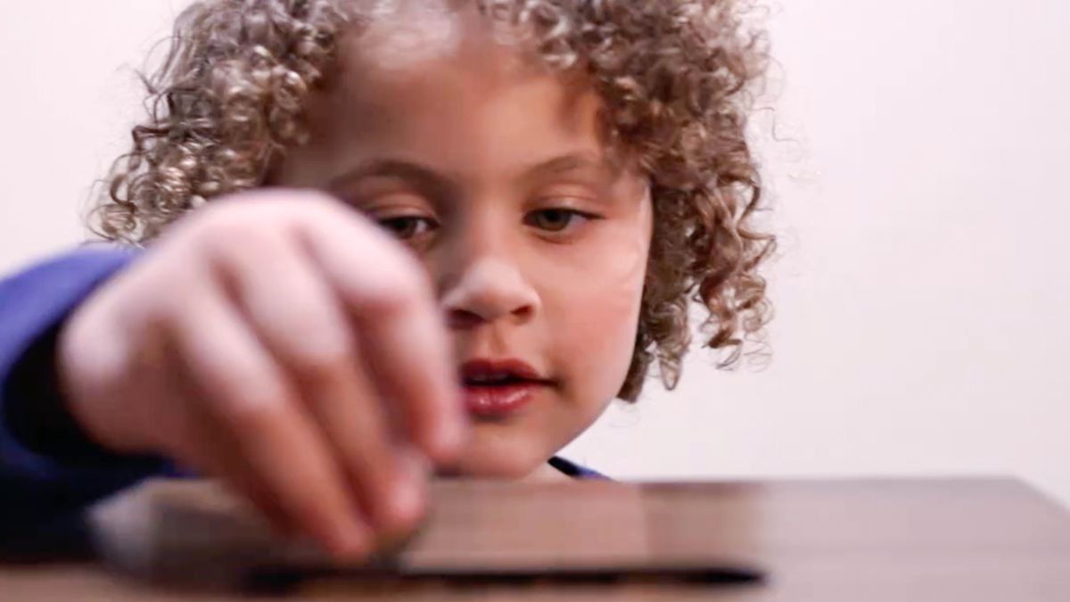 A young girl putting a donation in a contribution box.