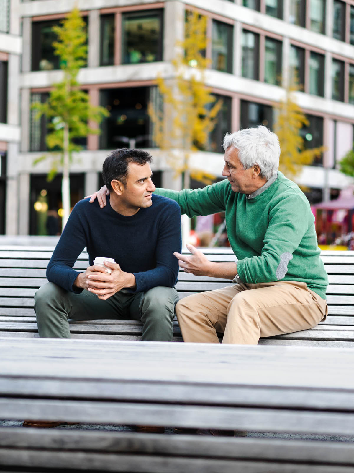 Um idoso fala de modo consolador com um homem mais jovem.