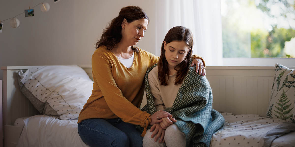 Uma mãe consolando sua filha que está deprimida.