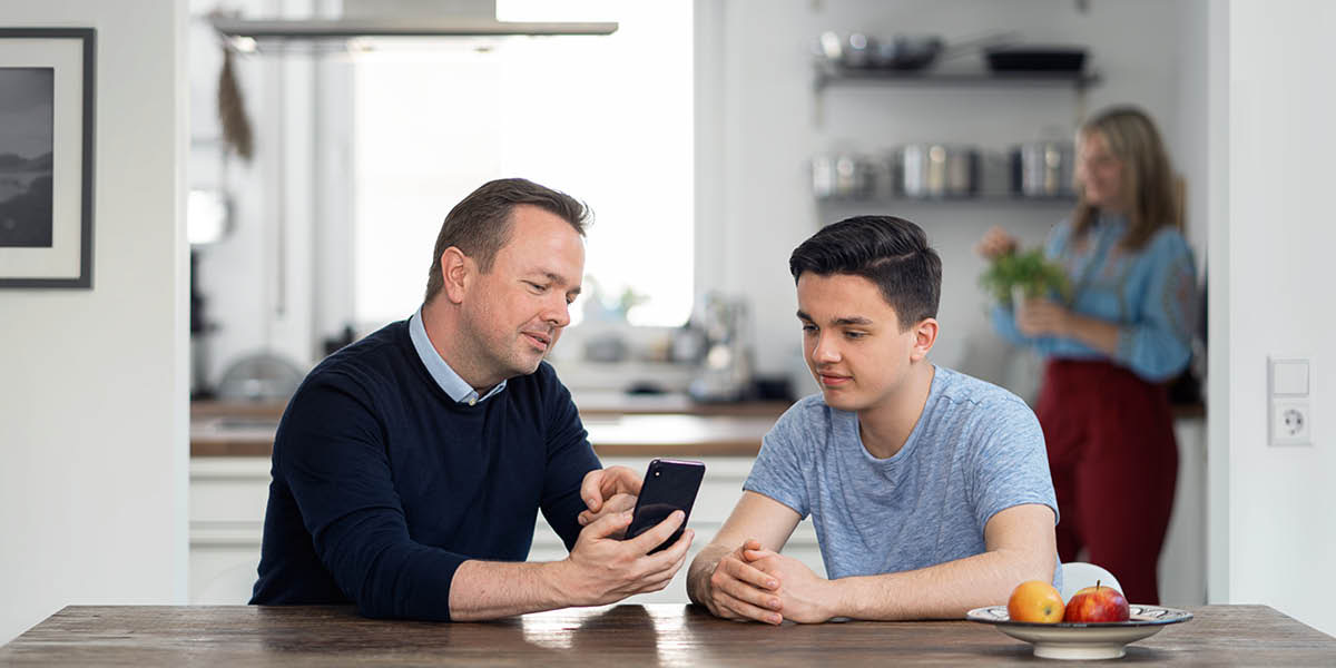 Um pai ensinando seu filho a usar um smartphone de maneira responsável.