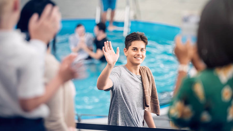 Um jovem acenando para a família e para os amigos antes de entrar na piscina do batismo