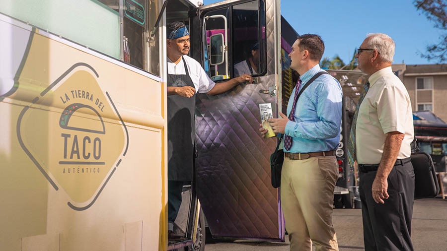 Um irmão mostrando um folheto para o cozinheiro de um food truck.