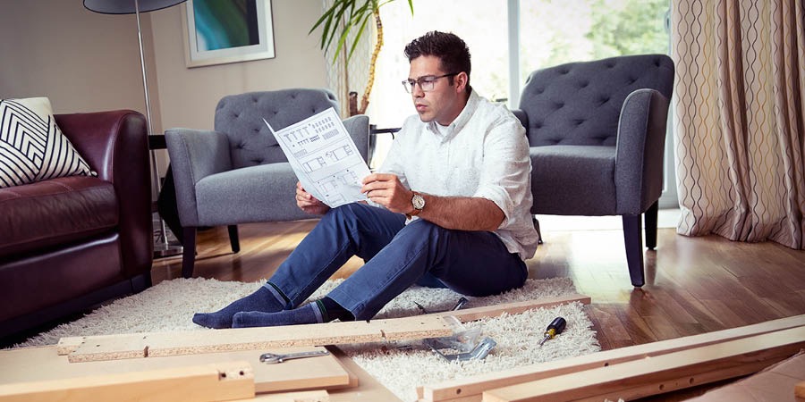 Un home llegint les instruccions del fabricant sobre com muntar un moble.