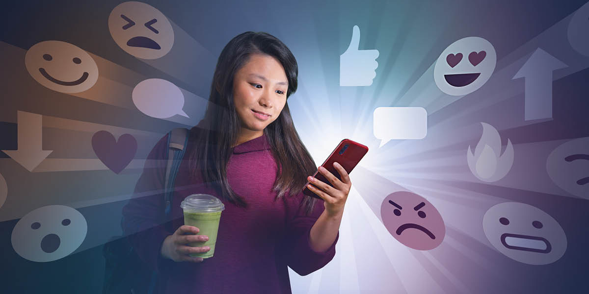 Una adolescent mirant el seu mòbil. Al seu voltant apareixen emojis.