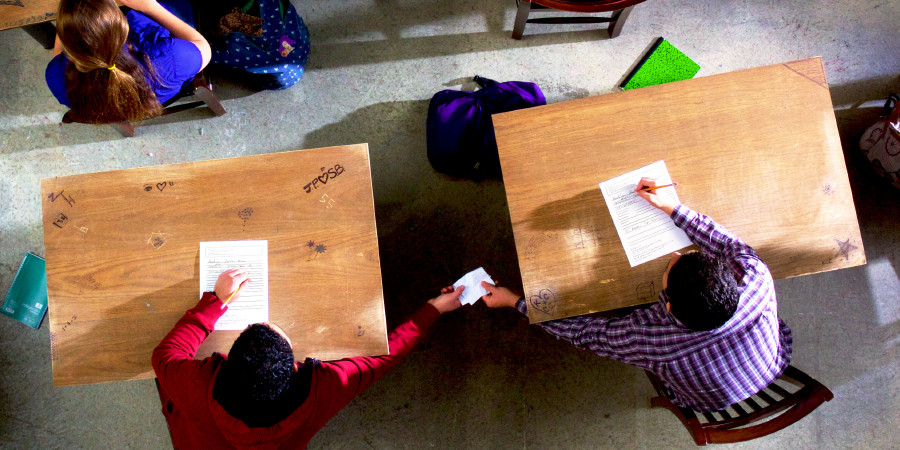 Un xic passa una xulla a un altre perquè copie en un examen