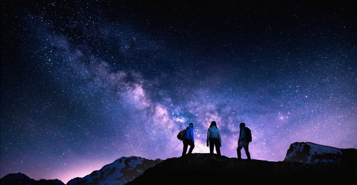 Excursionistes al cim d’una muntanya, observant el cel ple d’estreles.