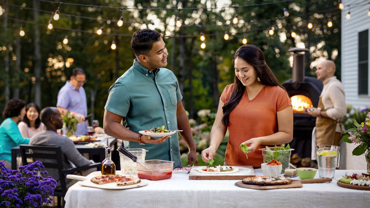 El solter i la soltera xerrant al jardí d’uns germans, que han convidat un grup a dinar.