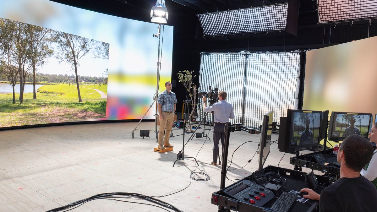 Brader diha sa studio nga nagtindog atubangan sa video wall. Parke ang makita sa screen. Ang ubang brader nagtesting sa equipment.