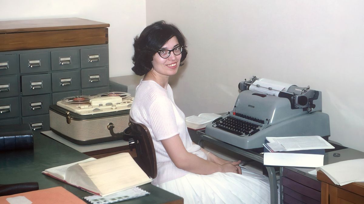 Si Irma naglingkod nga naay typewriter sa iyang atubangan ug tape recorder sa kilid.