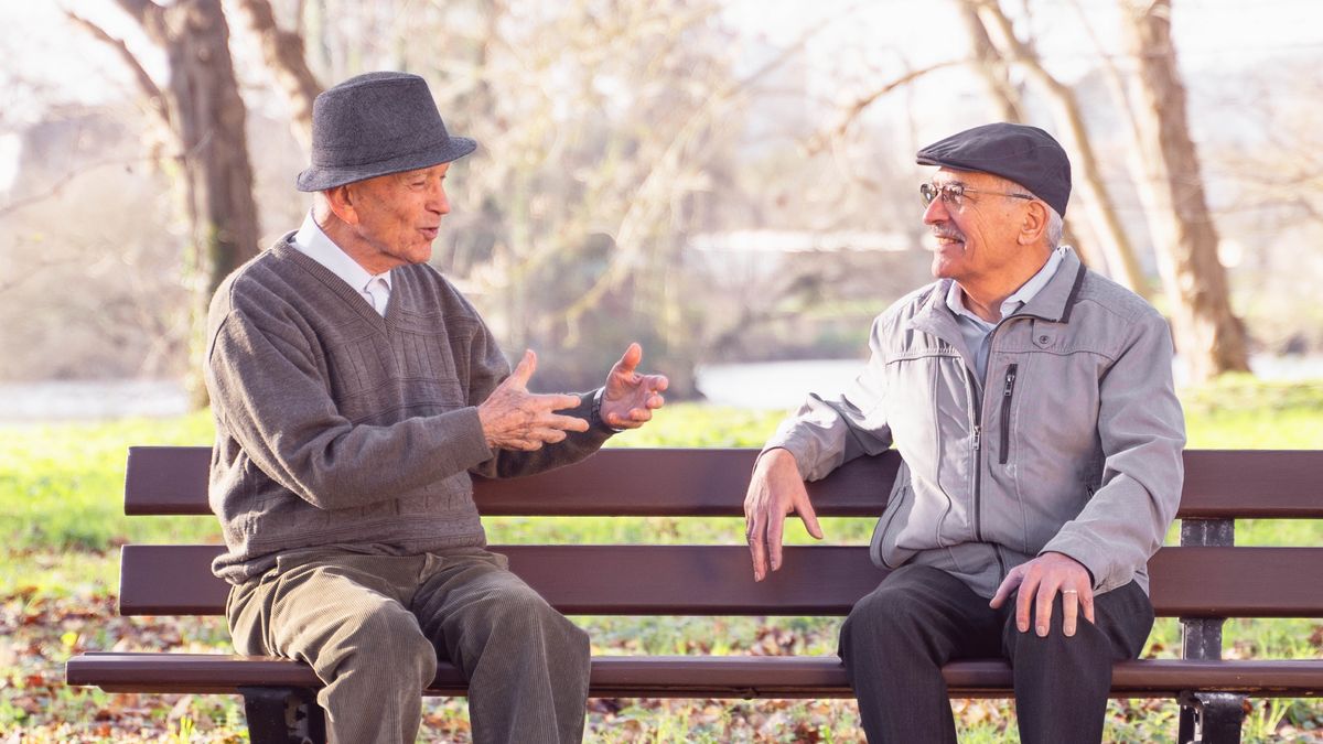 一個老弟兄坐在公園的長椅上跟人聊天。