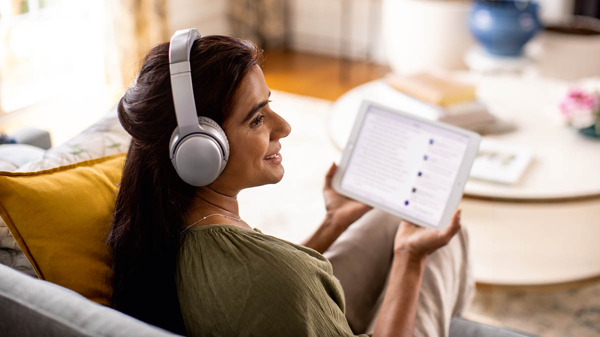 Sestra má na uších sluchátka a poslouchá audionahrávku ze svého tabletu