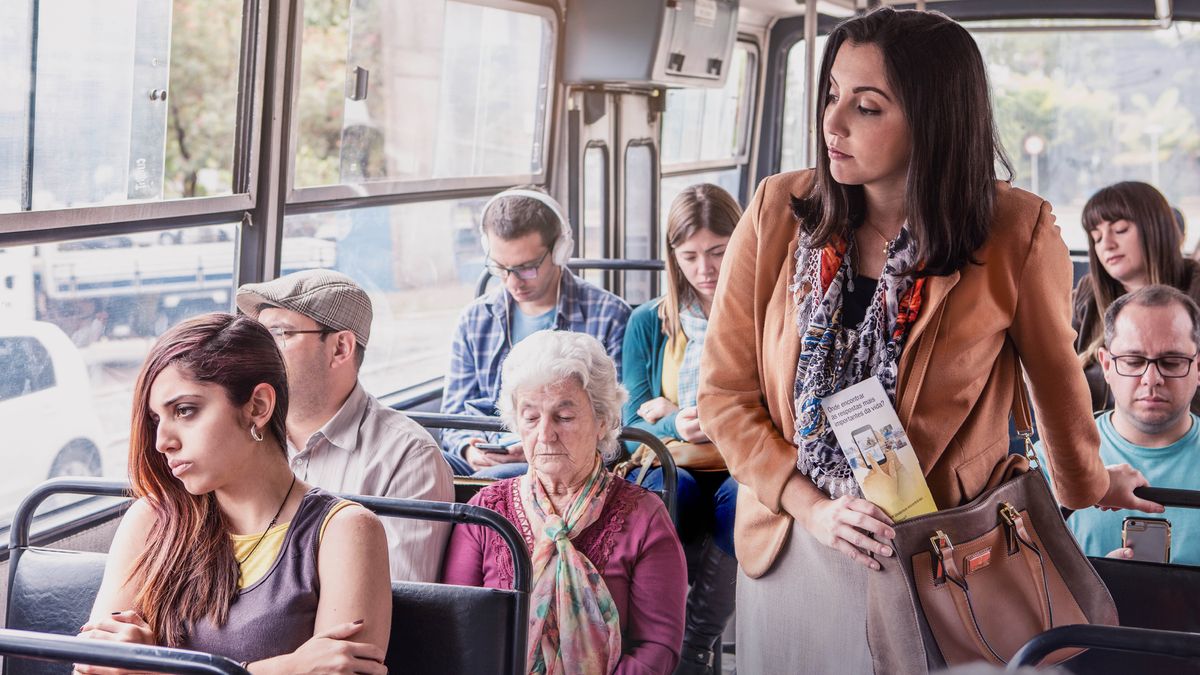 Sestra se v autobuse dívá na ženu, která vypadá zničeně. Ta sestra drží v ruce leták „Kde hledat odpovědi na zásadní životní otázky?“.