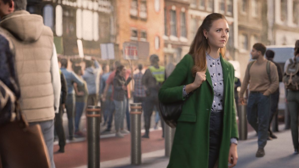 Sestra jde po rušné ulici, kde zrovna probíhá protest, a s klidným výrazem se dívá před sebe.