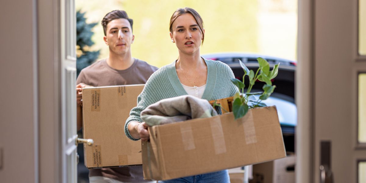 一名男子和一名女子，把他们的私人物品搬进房子里。