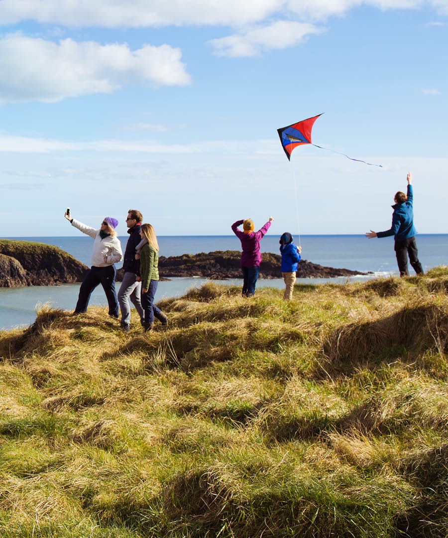 Folk ved havet flyver med drage og tager billeder