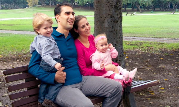 En familie der sidder på en bænk i en park