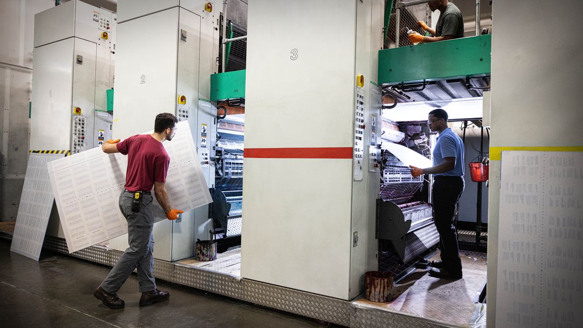 Brüder wechseln Druckplatten und warten eine große Druckmaschine.