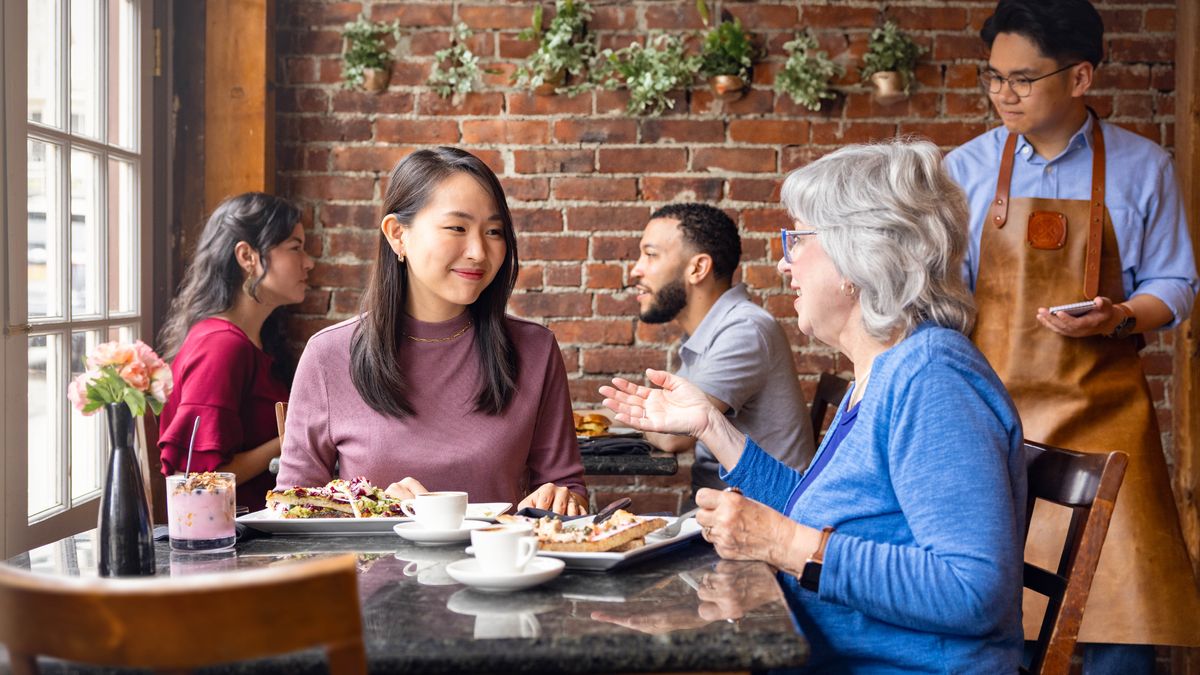 Eine junge Schwester ist mit einer älteren Schwester im Restaurant und hört sich aufmerksam ihren Rat an.