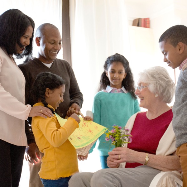 Eine Familie kümmert sich ganz lieb um eine ältere Dame, die aus einem anderen Land kommt