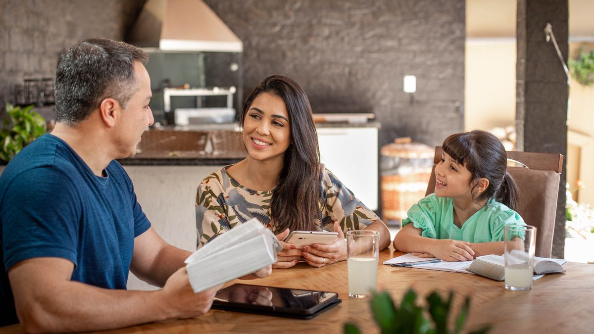 Die Mutter zusammen mit ihrem Mann und ihrer Tochter beim Familienstudium. Sie strahlt Freude aus.