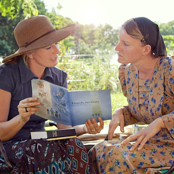 A sister preaches to a woman in Paraguay, using a publication in Low German