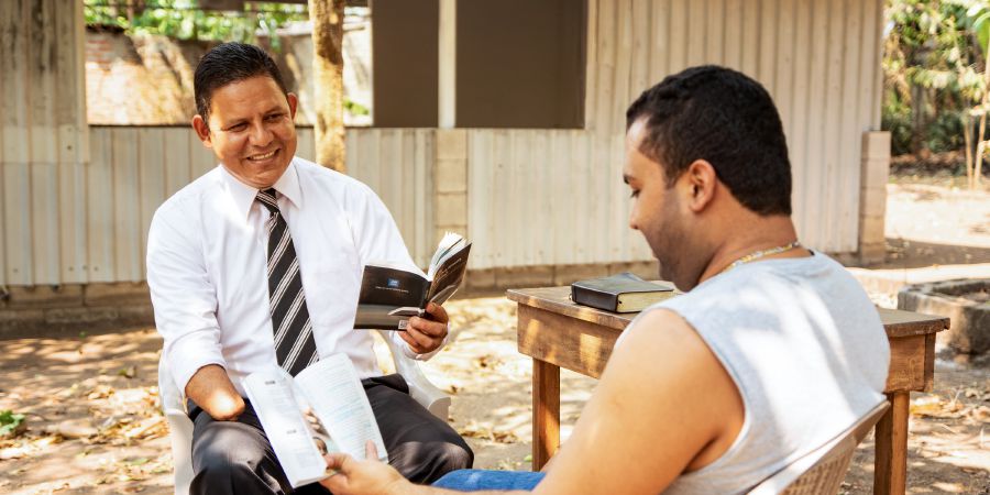 Óscar Serpas dando clases de la Biblia a un hombre
