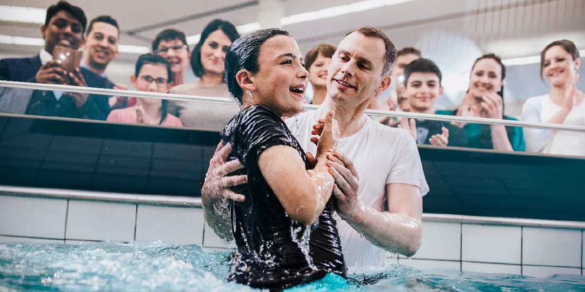 Un joven bautizándose en una piscina.