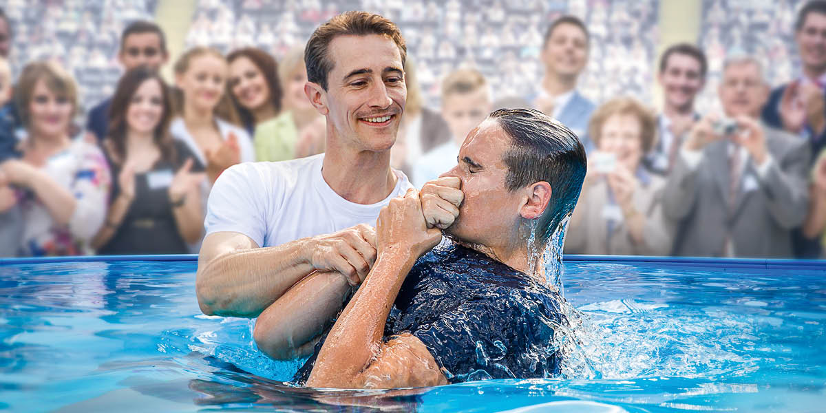 Un joven bautizándose en una piscina en una asamblea de los testigos de Jehová.