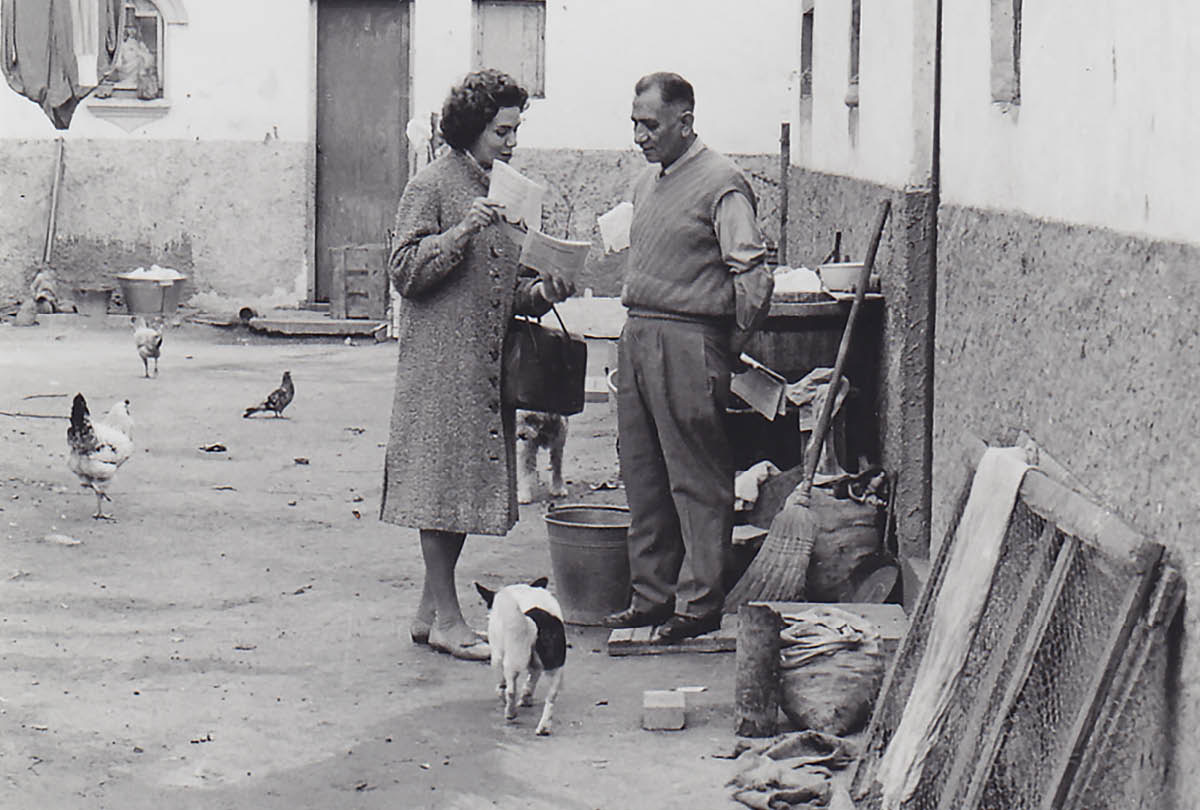 En una calle donde hay pollos y perros, Phyllis le predica a un hombre en la puerta de su casa.